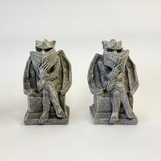 A pair of seated bookworm gargoyles bookends with legs crossed on a white background. 

House Parts home decor handmade Atlanta gargoyle grotesque whimsical fantasy mystical creature. Unique gift for fans of fantasy, dungeon, or dinosaurs. Unique Christmas gift for someone who has everything or fantasy lovers. Gothic, medieval, unique, artisan, craft, detail, specialty, a gift that no one else has, special, protective, female owned business, family small business, odd, quirky gifts