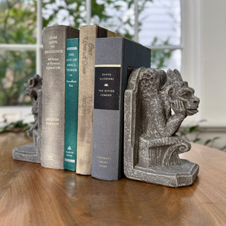 A pair of gothic gargoyles bookends sitting on a throne holding up 3 books between them.  Sitting on a wooden tabletop with a partial view of a window

House Parts home decor handmade Atlanta gargoyle grotesque whimsical fantasy mystical creature. Unique gift for fans of fantasy, dungeon, or dinosaurs. Unique Christmas gift for someone who has everything or fantasy lovers. Gothic and medieval