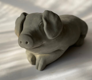 A gray concrete sculpture of a lying pig with a playful expression on a white background.  This is one happy pig

House Parts handmade, crafted, artisan, high quality, statues, busts, and figurines.  Unique gifts for everyone. Indoor decorations, Outdoor statues and garden items. Thoughtful gift, animal lovers, rabbit lovers, instead of pet, small business, female owned family business, rabbit, bunny, dog, turtle, frog, clam shell