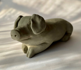 A gray concrete sculpture of a lying pig with a playful expression on a white background.  This is one happy pig

House Parts handmade, crafted, artisan, high quality, statues, busts, and figurines.  Unique gifts for everyone. Indoor decorations, Outdoor statues and garden items. Thoughtful gift, animal lovers, rabbit lovers, instead of pet, small business, female owned family business, rabbit, bunny, dog, turtle, frog, clam shell