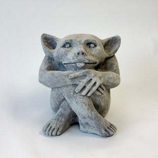 Sitting cement gargoyle statue with bat-like features and his tongue sticking out on a white background. House Parts home decor handmade Atlanta gargoyle grotesque whimsical fantasy mystical creature. Unique gift for fans of fantasy, dungeon, or dinosaurs. Unique Christmas gift for someone who has everything or fantasy lovers