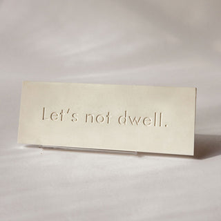 A rectangular white plaque with the phrase 'Let's not dwell' on a white background. Stand sold separately

House Parts handmade, crafted, artisan, high quality, statues, busts, and garden and animal figurines.  Unique gifts for everyone. Indoor decorations, Outdoor statues and garden items. Fantasy, whimsical, thoughtful gifts, original gift idea, shop small business, plaster, concrete, Clam shell, Gargoyles, Alice in Wonderland, animal lover gifts, pet memorial