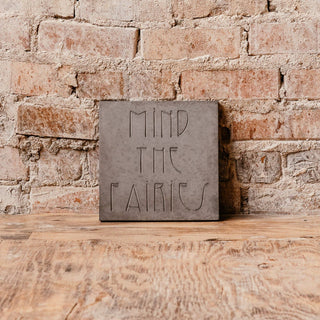 Decorative garden steppingstone that warns you to "Mind the Fairies" set on a wooden tabletop against a brick background

House Parts handmade, crafted, artisan, high quality, statues, busts, and garden and animal figurines.  Unique gifts for everyone. Indoor decorations, Outdoor statues and garden items. Fantasy, whimsical, thoughtful gifts, original gift idea, shop small business, plaster, concrete, Clam shell, Gargoyles, animal lover gifts, pet memorial Decorative Garden steppingstone