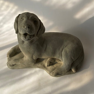A gray concrete statue of a lying dog with a joyful expression. tongue hanging out just a bit like he is panting from playing hard.  He is a happy dog.

House Parts handmade, crafted, artisan, high quality, statues, busts, and figurines.  Unique gifts for everyone. Indoor decorations, Outdoor statues and garden items. Thoughtful gift, animal lovers, rabbit lovers, instead of pet, small business rabbit, bunny, dog, turtle, frog, clam shell, animal lover gifts, pet memorial