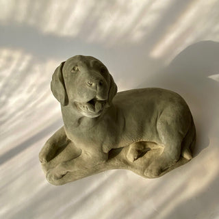 Slightly turned for a different view. A gray concrete statue of a lying dog with a joyful expression. tongue hanging out just a bit like he is panting from playing hard.  Sweet dog.

House Parts handmade, crafted, artisan, high quality, statues, busts, and figurines.  Unique gifts for everyone. Indoor decorations, Outdoor statues and garden items. Thoughtful gift, animal lovers, rabbit lovers, instead of pet, small business rabbit, bunny, dog, turtle, frog, clam shell, animal lover gifts, pet memorial